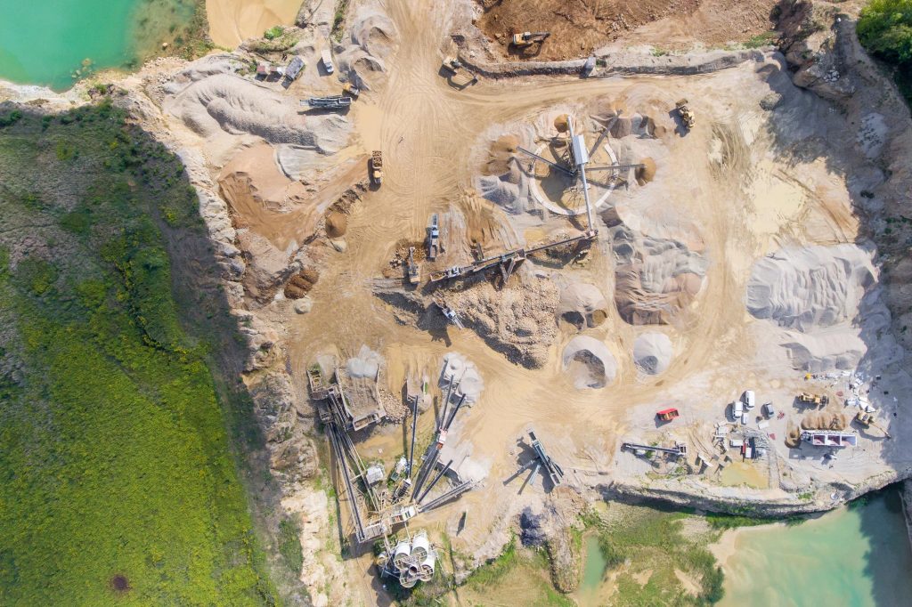 Drone flying over quarry measuring stockpiles with advanced technology for accurate volume analysis and inventory management.